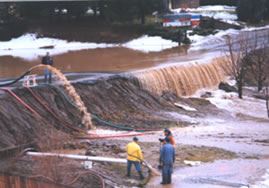 People manning a packed earth dam as stormwater drains over and away from it on Lyle Avenue in 1995