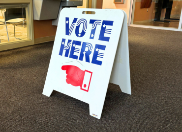 A vote here sign in a hallway