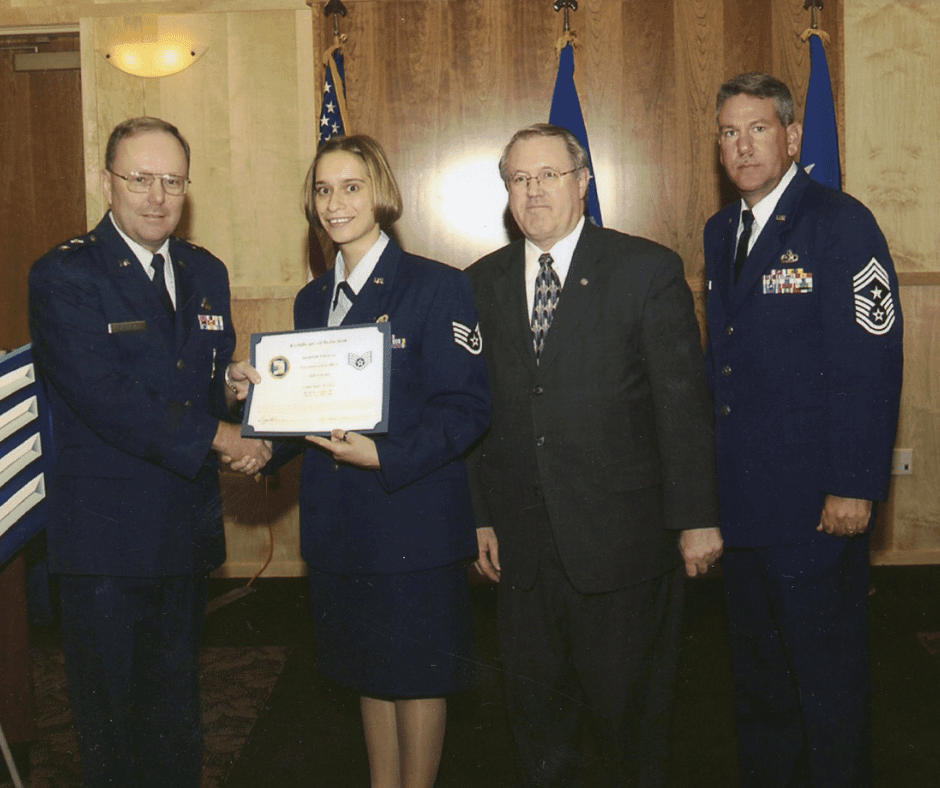 A Sergeant in Air force uniform receives an award certificate with three others.